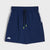 Navy blue athletic shorts with a white patterned side stripe, a black drawstring with neon green tips, and a white logo on the lower left leg, shown against a light gray background.