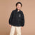 A young child wearing a black half-placket pullover sweatshirt with white contrast stitching and 'Sport Star Play Studio' text on the chest, paired with cream pants and a black beret, against a solid tan studio background.