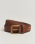 Brown leather belt with gold buckle on a light beige background