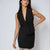A woman modeling a black sleeveless wrap vest dress with a deep V-neckline, double-breasted waist, and a silver beaded trim at the hem, set against a plain light gray background.