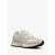 A single low-top sneaker in light beige and off-white leather with a black outsole, shown from a side profile on a clean white background.