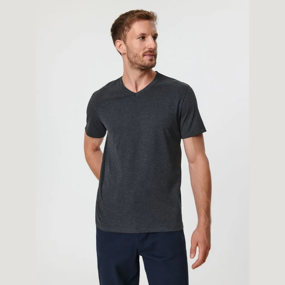 A man wearing a dark heather gray v-neck t-shirt and navy blue pants, standing against a light gray studio background.