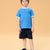 A young boy modeling a light blue ringer t-shirt with white trim and a dark navy shorts, standing against a solid beige background.