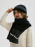 Child wearing a black knit hat and scarf with a white background