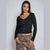 A woman modeling a black long-sleeve ribbed knit cropped cardigan with a scalloped hem and front buttons, paired with leopard print pants, against a light gray studio background.