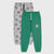 Two pairs of kids' sweatpants displayed flat against a light gray background. The front pair is bright green with a small soccer-themed crest on the left thigh and white drawstrings.