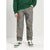 A child wearing gray heathered jogger pants, a green sweatshirt, and green and white sneakers, standing against a light gray studio background.