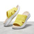 A pair of yellow open-toe slide sandals with thick white soles and beige footbeds, displayed on a light gray surface against a white background.