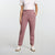 A woman modeling a white short-sleeve t-shirt with thin pink horizontal stripes and high-waisted, straight-leg dusty rose pants, paired with white sneakers, against a light gray studio background.