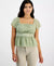 Woman wearing a light green top with lace detail on a white background