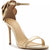 A metallic gold high-heeled sandal with a stiletto heel, thin front strap, ankle strap with a buckle, and a large decorative braided flower detail on the outer ankle.