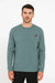 Man wearing a teal long-sleeve shirt with a small brown logo on a white background