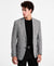 Man wearing a gray checkered blazer over a black shirt on a white background