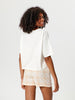 Woman wearing a white oversized t-shirt and plaid shorts on a plain background