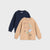 Two long-sleeve crewneck sweatshirts for kids, one in navy blue and one in beige with a colorful dinosaur graphic and the text 'DINOSAURS SPECIES!', displayed on a light gray background.