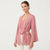 A woman modeling a pink and white striped kimono cardigan with a tie waist, worn over a dusty pink top and white pants against a plain white background.