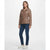 A woman modeling a brown faux-leather jacket with a zip-up front, collar, and matching belt, paired with dark blue jeans and white sneakers, against a plain white studio background.