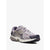A Nike running shoe in a mix of lavender, gray, and navy blue, featuring a gold Swoosh accent, set against a plain light gray background.