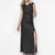 A blonde model wearing a sleeveless, floor-length black textured gown with a high thigh slit, standing against a plain white studio background.
