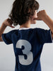 Child wearing a blue sports jersey with the number 3 on a plain background