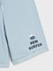 Light blue shorts with 'New Surfer' text and wave graphic on a white background