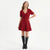 A woman modeling a short-sleeve red sparkly dress with a V-neck and bow detail, paired with black knee-high boots, against a plain white studio background.