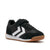 A black and white low-top sneaker with a hook-and-loop strap closure and a gum rubber sole, shown from a side profile on a light gray background.