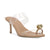A single women's heeled sandal with a nude beige footbed and toe loop, featuring transparent clear straps and a gold-tone decorative knot detail on the toe post, shown against a plain white background.