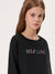 Young girl wearing a black sweatshirt with 'SELF LOVE' in colorful letters on a white background