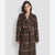 A woman modeling a brown wool-blend coat with a tan windowpane plaid pattern, featuring a shawl collar, belted waist, and front buttons, set against a light gray studio background.