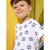 A young boy wearing a white short-sleeve t-shirt with a black and white soccer ball pattern, set against a bright yellow background.