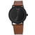 Watch with black dial and brown leather strap on a white background