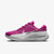 A Nike running shoe in vibrant magenta pink with a metallic silver Swoosh and a thick white cushioned sole, shown from a side profile on a light gray background.