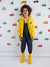 Child wearing a yellow raincoat and boots standing in front of a wall with vehicle pattern