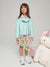 A girl wearing a light blue biker jacket with a classic collar, zip fastening, and two pockets, standing next to a plush unicorn toy.