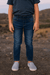 Person wearing a navy shirt and blue jeans standing in a desert landscape.