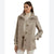 A woman wearing a beige and brown plaid wool coat over a cream turtleneck sweater and white pants, photographed against a plain white studio background.