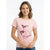 A woman wearing a light pink crewneck t-shirt with a graphic print of a flamingo wearing a pirate hat, paired with blue jeans against a plain white background.