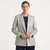 A woman modeling a light gray textured double-breasted blazer over a navy blue top and navy trousers, photographed against a clean white studio background.