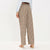 A person shown from the back wearing beige plaid wide-leg trousers with a brown belt, a light blue shirt, and beige heels against a plain white studio background.