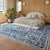 Bedroom with a blue and white patterned rug, bed, and decor.