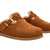 A pair of women's slip-on clogs in warm brown suede with a soft beige shearling lining and a decorative gold buckle strap, shown on a plain white background.