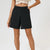 A model wearing black high-waisted shorts with a matching black belt, paired with a cream crochet crop top, shown against a plain white studio background.