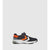 A single athletic sneaker shown in profile against a light gray background. The shoe features a dark navy blue mesh upper, a bright orange chevron accent on the side, a white midsole, and a hook-and-loop strap closure.
