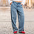 A person wearing light blue wide-leg denim jeans, a white cropped top, and red shoes, standing on a cobblestone street.