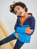 Child wearing a blue and orange jacket with a plain background