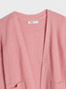 Pink knitted cardigan with a brand label on a light gray background