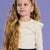 Young girl with long blonde hair wearing a floral headband against a purple background