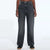 A model is shown from the waist down wearing a pair of dark gray wide-leg jeans with a faded wash, paired with black shoes, against a plain white studio background.