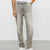 A person wearing light gray washed denim jeans with a faded finish, paired with a white t-shirt and white sneakers, shown from the waist down against a plain light gray studio background.